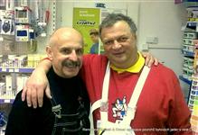 Karel Koubek a Miroslav Koubek v nových montérkách černé a bílé se drží kolem ramen v prodejně na školení a s úsměvem